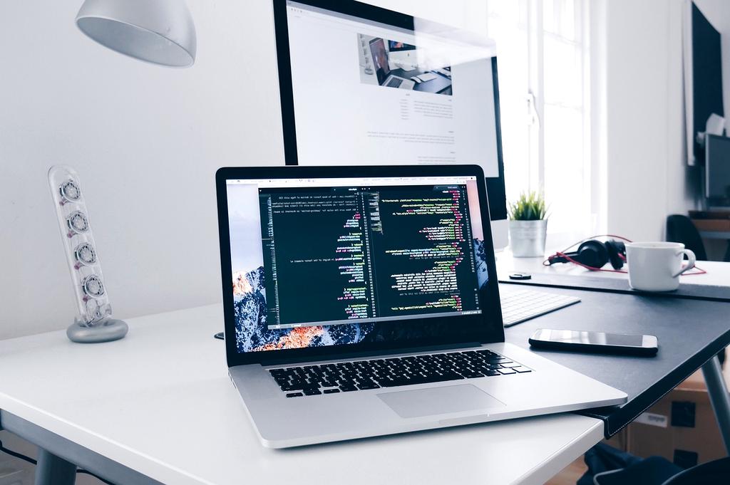 Hands coding on a laptop with multiple monitors displaying AI models